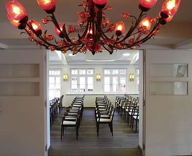 Tagungsraum in Kinobestuhlung mit rotem Kronleuchter im Vordergrund