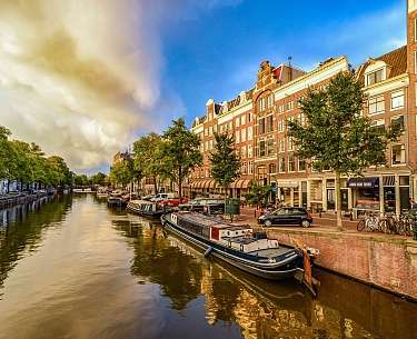 Abendfoto von farbigen Häusern im niederländischen Stil mit Spiegelung im Wasser in Amsterdam