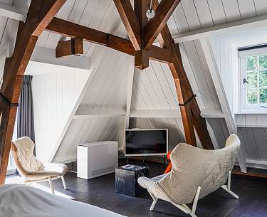 Zimmer mit freigelegten Holzbalken im ehemaligen Kutscherhaus 