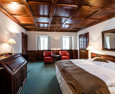 Uriges Hotelzimmer mit gemütlichem Bett und grünem Teppichboden
