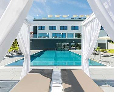 Eine Poolliege mit Vorhang an einem Außenpool eines Romantik Hotels in Europa 