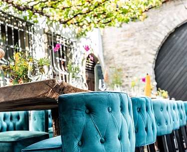 Blaue Stoffstühle stehen an einer Tafel im Außenbereich eines Romantik Hotels 