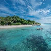 Türkisblaues Meer vor einer grünen Insel mit weißem Sandstrand