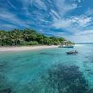 Türkisblaues Meer vor einer grünen Insel mit weißem Sandstrand