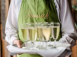 Blick auf Servierteller mit Sektgläsern und grüner Schürze