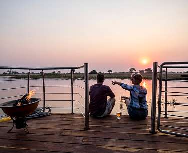 Paar genießt Sonnenuntergang am Kwando, Sambesi-Region, Namibia