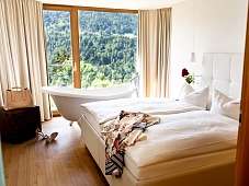 Ein Doppelbett und eine freistehende Badewanne im Romantik Hotel Das Schiff 