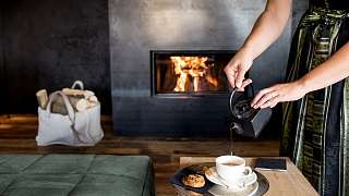 In einem exklusiven Wellnesshotel wird Tee an einem Lagerfeuer eingeschenkt 