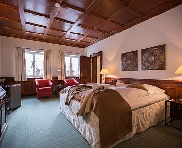 Geräumiges Hotelzimmer mit grünem Teppichboden und Holzakzenten