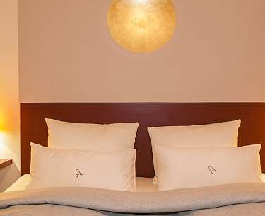 Blick auf die Kopfseite eines Doppelbetts mit weißen Kissen