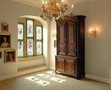 Ein Zimmer mit antiken Möbeln und einem Fenster, das Licht auf den Boden wirft