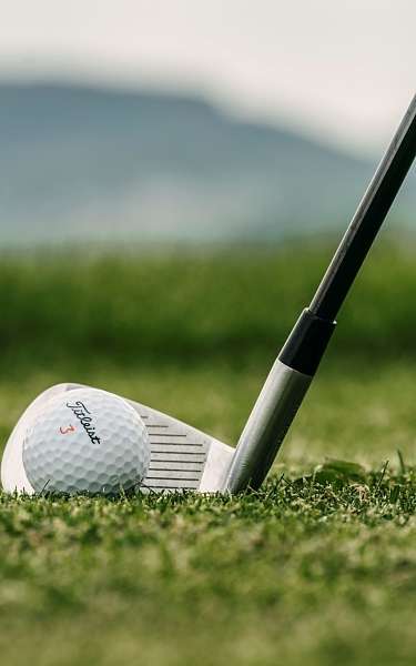 Ein Golfer schlägt im Golfurlaub einen Ball auf einem Fairway inmitten der Berge 