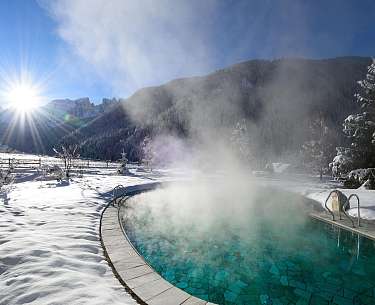 Blick auf den Außenpool inmitten von Schnee im romantischen Winterurlaub 