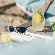 Sonnenbrille, Zeitung und sommerliche Limonade liegen auf einem Tisch