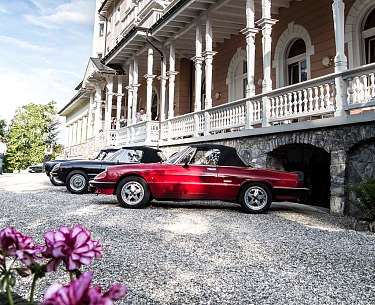 Zwei Oldtimer stehen im Oldtimer Urlaub vor einem alten Gebäude 