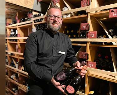 Ein Sommelier, der eine Flasche Wein in seinen Händen hält