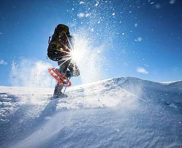 Ein Schneeschuhwanderer läuft mit einem Rucksack im Schneeurlaub