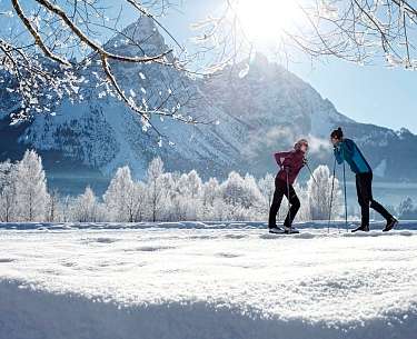 Ein Pärchen steht mit Langlaufski im romantischen Winterurlaub in Schnee 