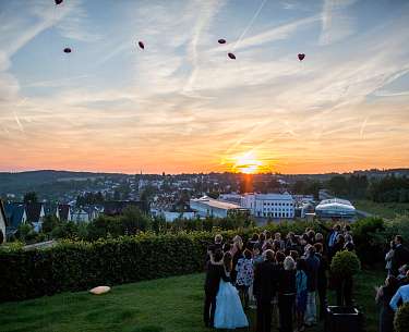 Hochzeitspaar und Gäste lassen Ballons im Sonnenuntergang steigen