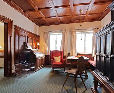 Uriges Hotelzimmer mit gemütlicher Sitzecke und grünem Teppichboden