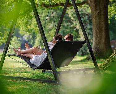 Zwei Hotelgäste entspannen in einem schönen Wellnesshotel auf einer Hängeliege 