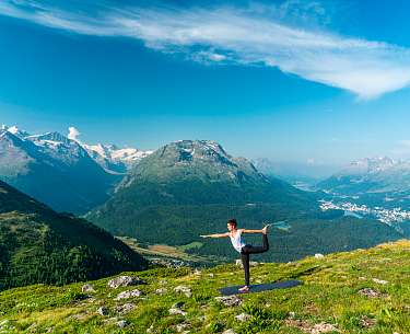 Eine junge Frau macht auf einem Berg nahe eines Wellnesshotels Yoga im Sommer 